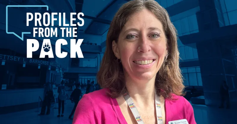 Shalako Thomas in bright pink shirt in front of a Madison College photo of windows in Gateway entrance of the Truax Campus.