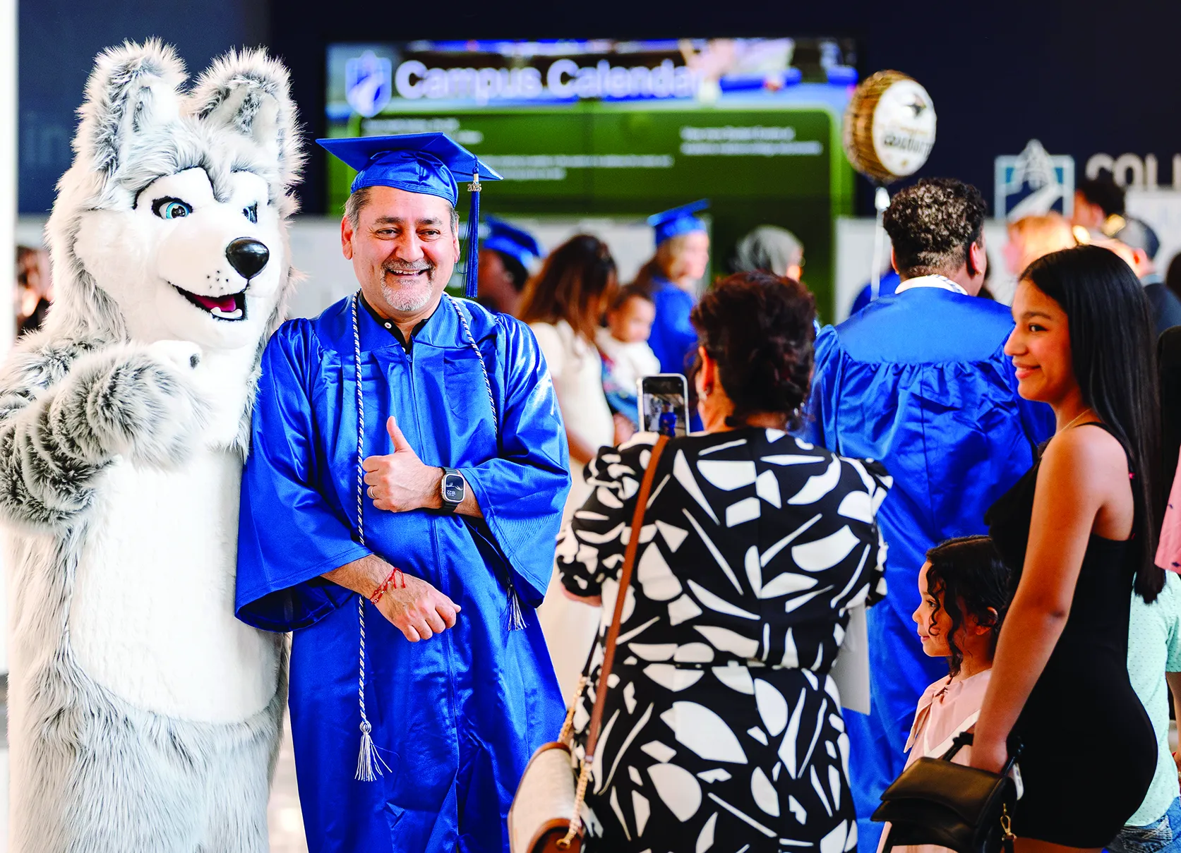 2025 High School Completion Program male graduate posing with Wolfie mascot.