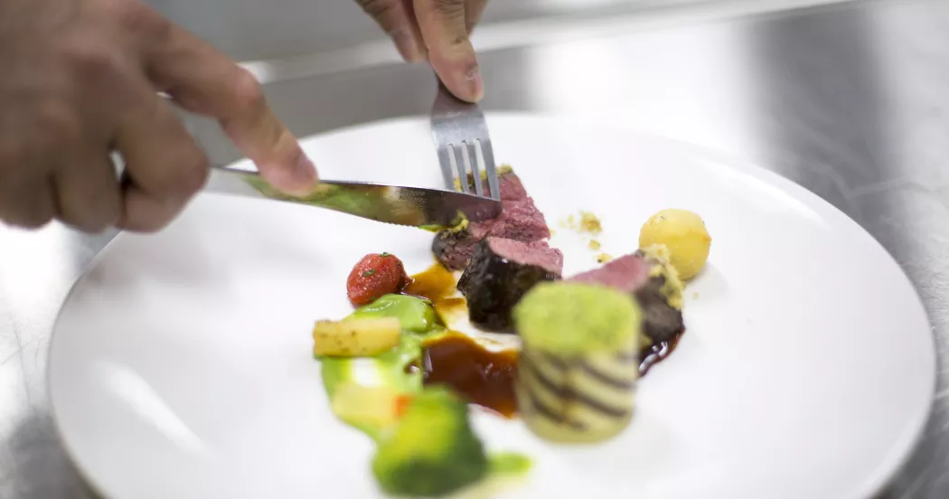 Person cuts meat with knife and fork. 