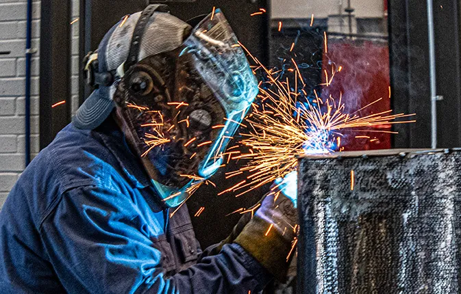 Student welding with sparks flying