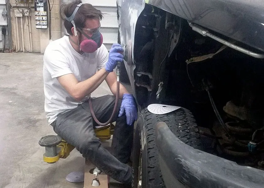 auto collision repair student sanding a car's side panel