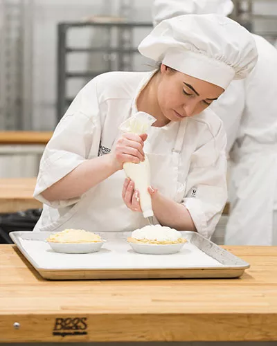baking student applying a cake piping technique