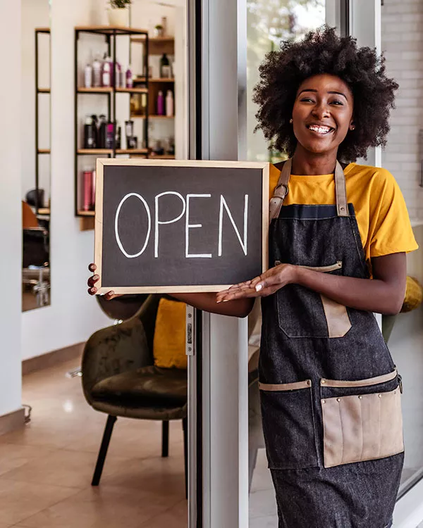an entrepreneur holding an open sign for their new business