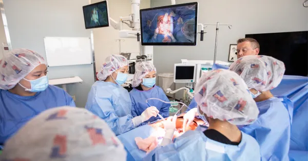 Students in surgical tech lab in blue scrubs and holding medical instruments.