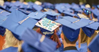 Photo of students at graduation ceremony, viewed from the back, showing their caps.