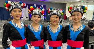 Photo of four Hmong women posing in traditional clothing.