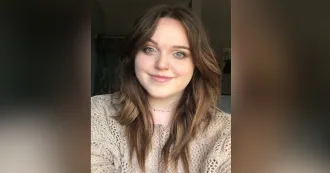 Photo of Callie Blackley with brown sweater and dark background.