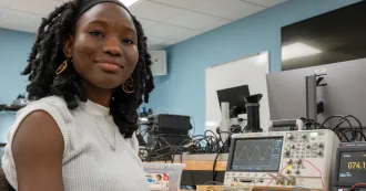 Josephine sitting as a desk in a Madison College classroom.