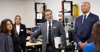 four people in an IT classroom with computers and wires in background.