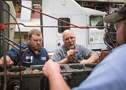 instructor and student looking at an engine part