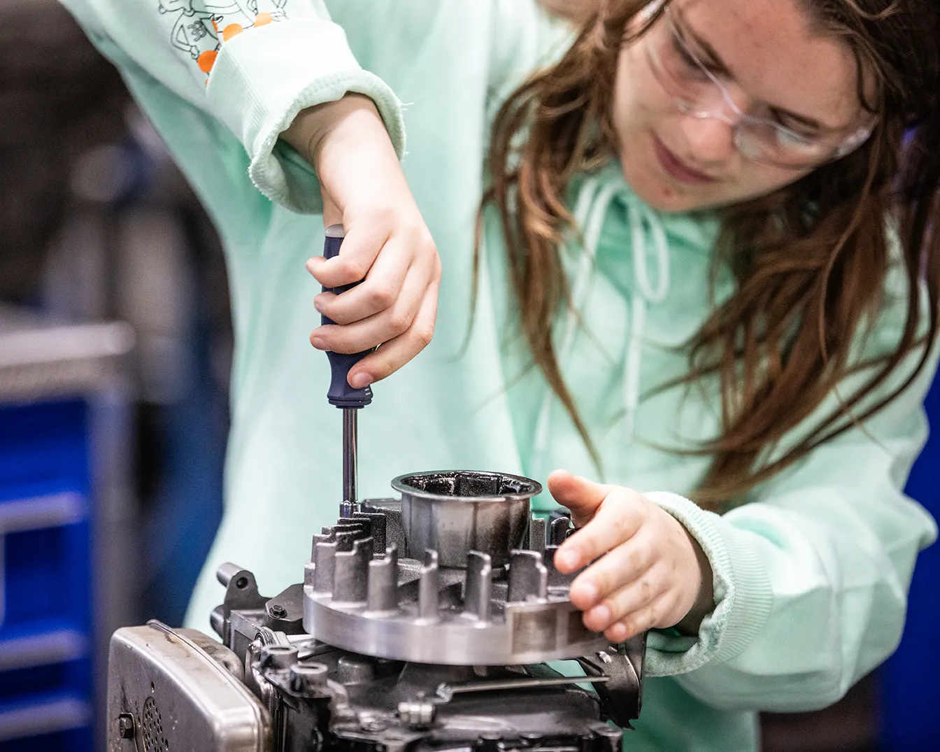 student using a screwdriver to open a small engine.