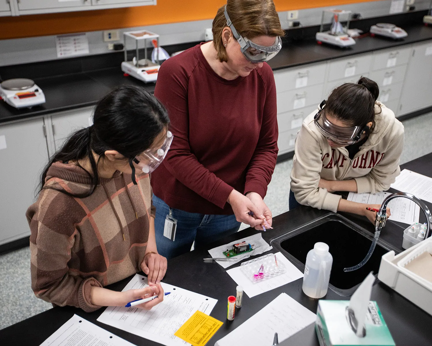 facutly helping two students in a lab