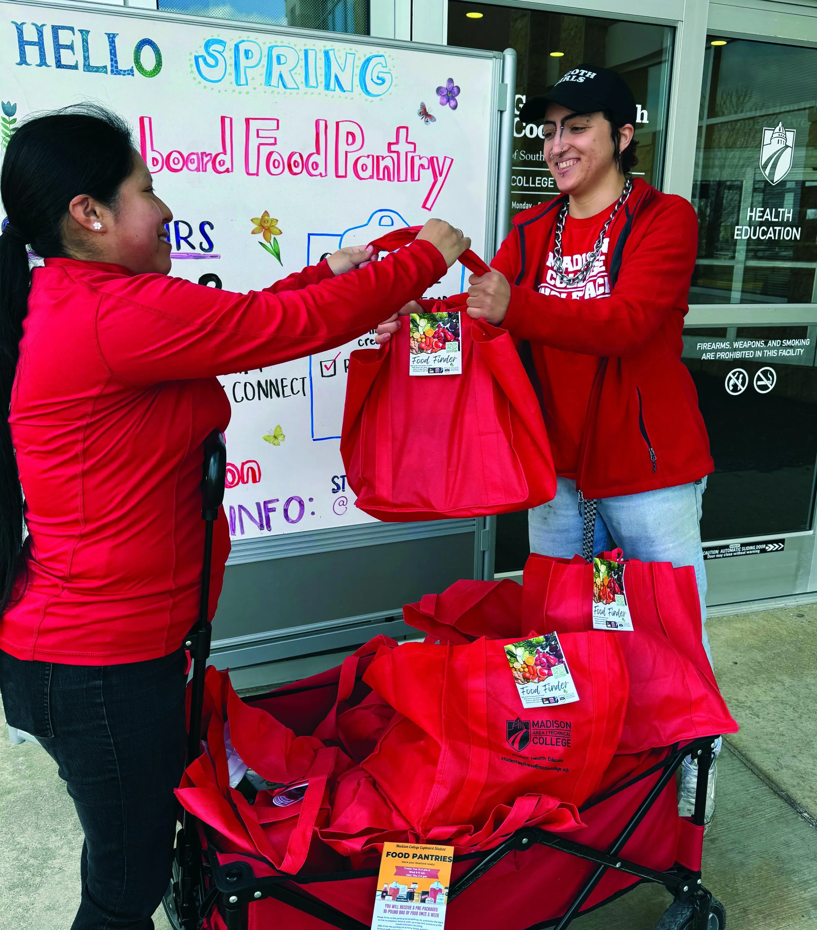 Students Michel and Riley distributing food in red bags to clients.