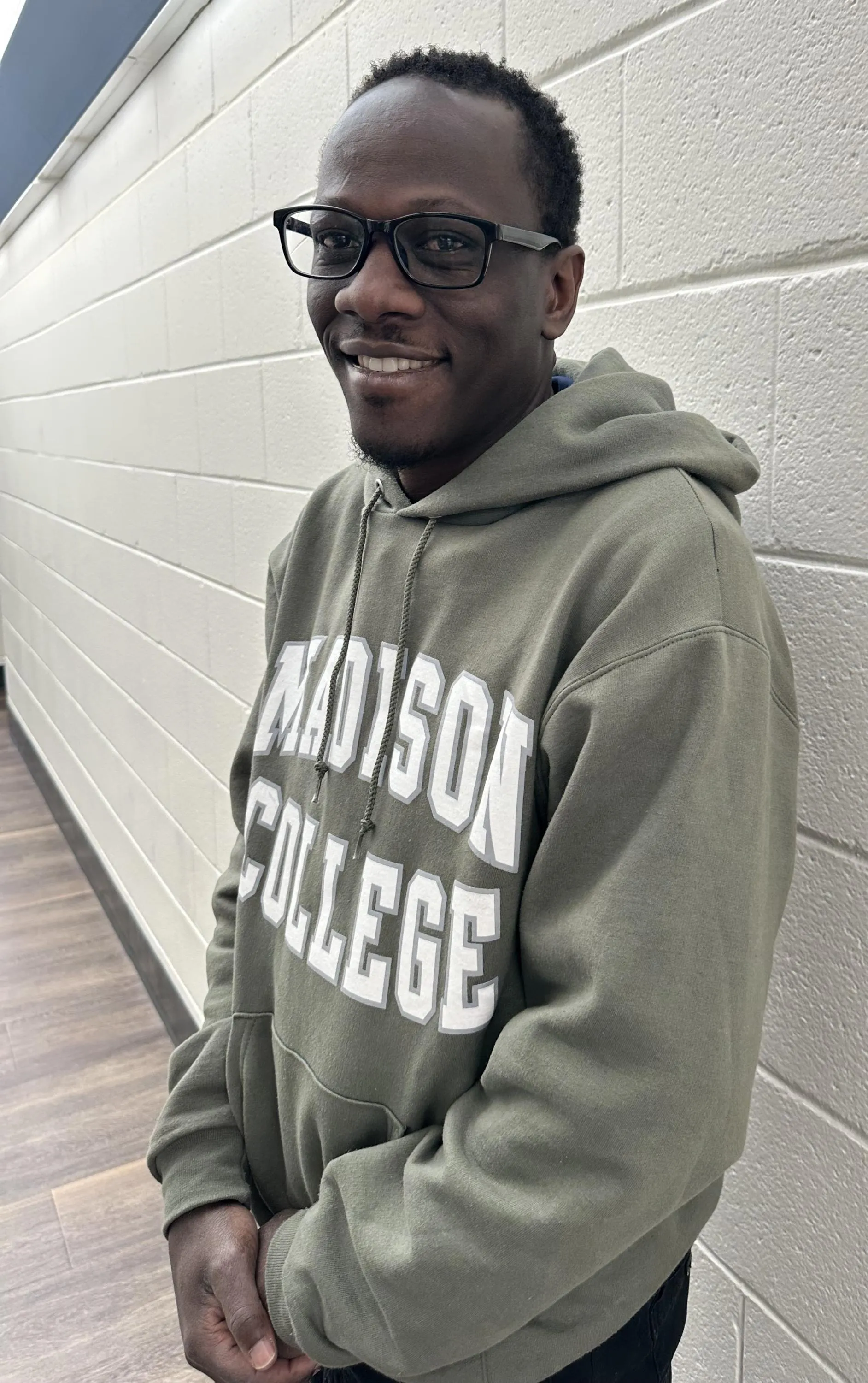 Madison College Reedsburg Lead Custodian Franco Okello poses for a photo in a hallway.