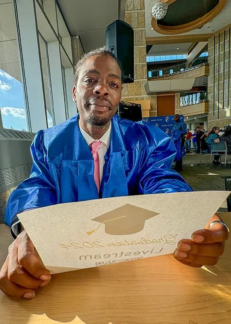 person sitting at table holding their diploma proudly