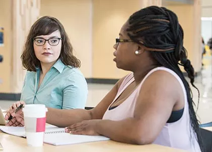Two students sitting at a table talking