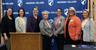 Photo of Madison College and UW-Whitewater leaders standing in front of a Madison College logo wall.