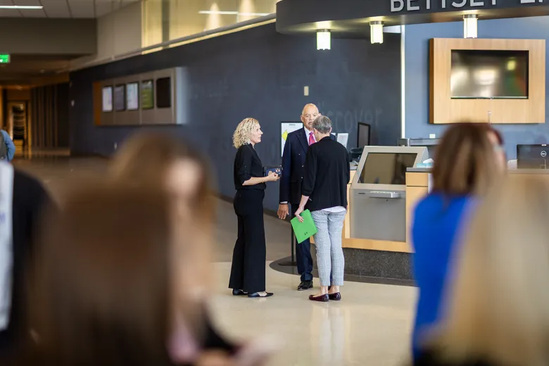 Three people talking in the background. Blurry heads in foreground.