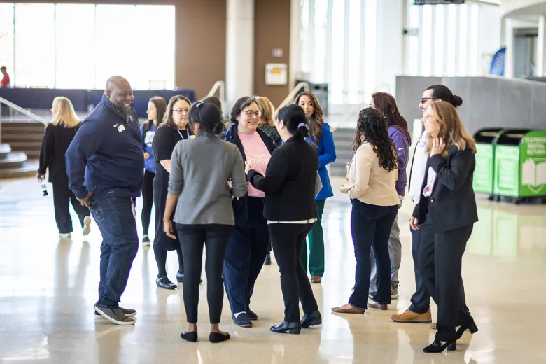 A group of people smiling and talking in a large open space