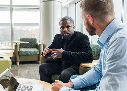 Two professionals are seated and engaged in conversation.
