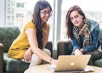 Two students looking at a mac laptop.