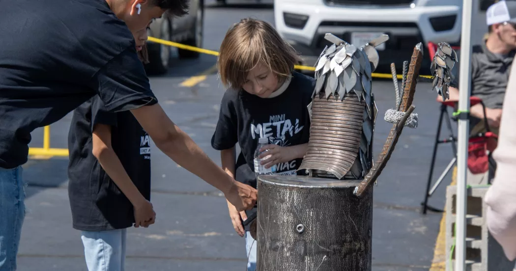 Metal Mania youth looking at welding creations