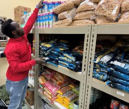 Madison College student Janvier Mukunzi stocking food in the Cupboard Student Food Pantry.