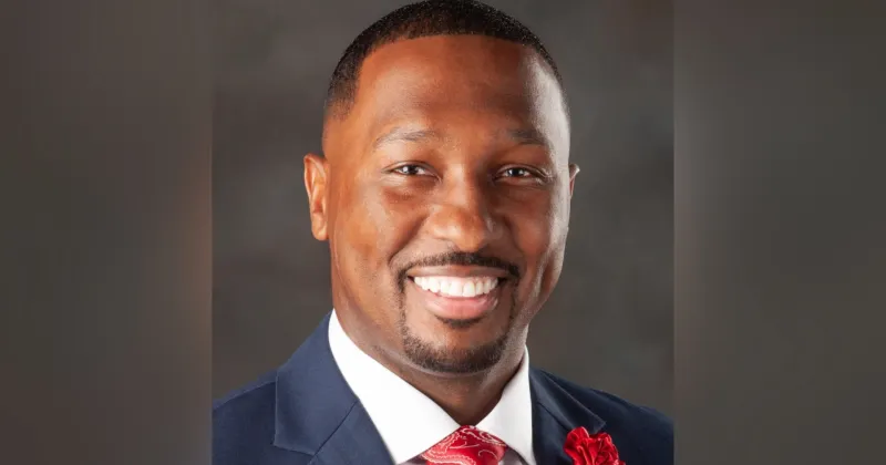 Close up headshot of Donald Dantzler, wearing a blue blazer, red tie. 