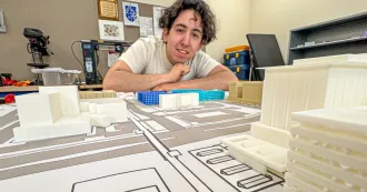 Student Sergio Perez looks over a building model on a table.