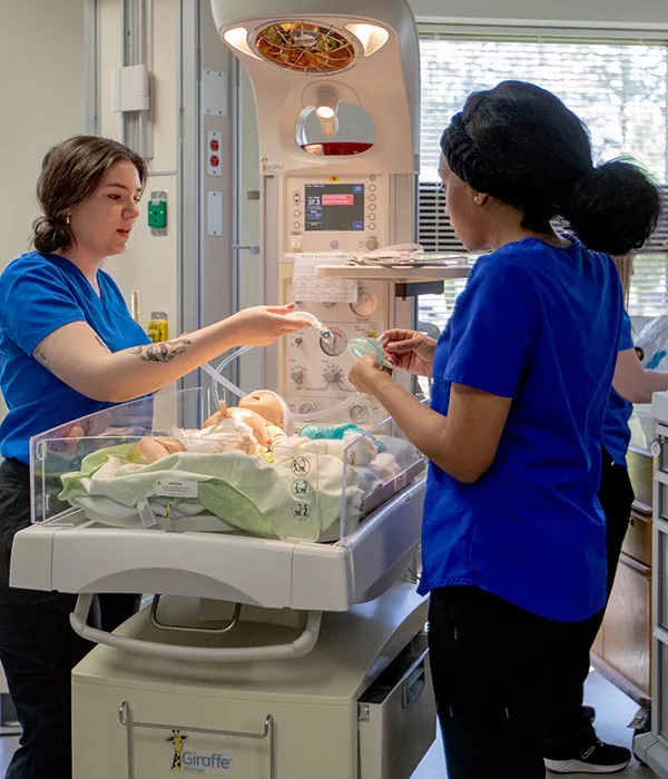 Madison College nursing students practicing techniques on an infant medical mannequin