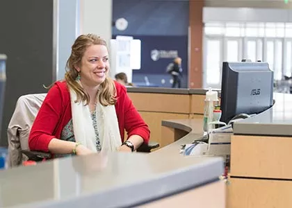 Student seated behind a reception counter.