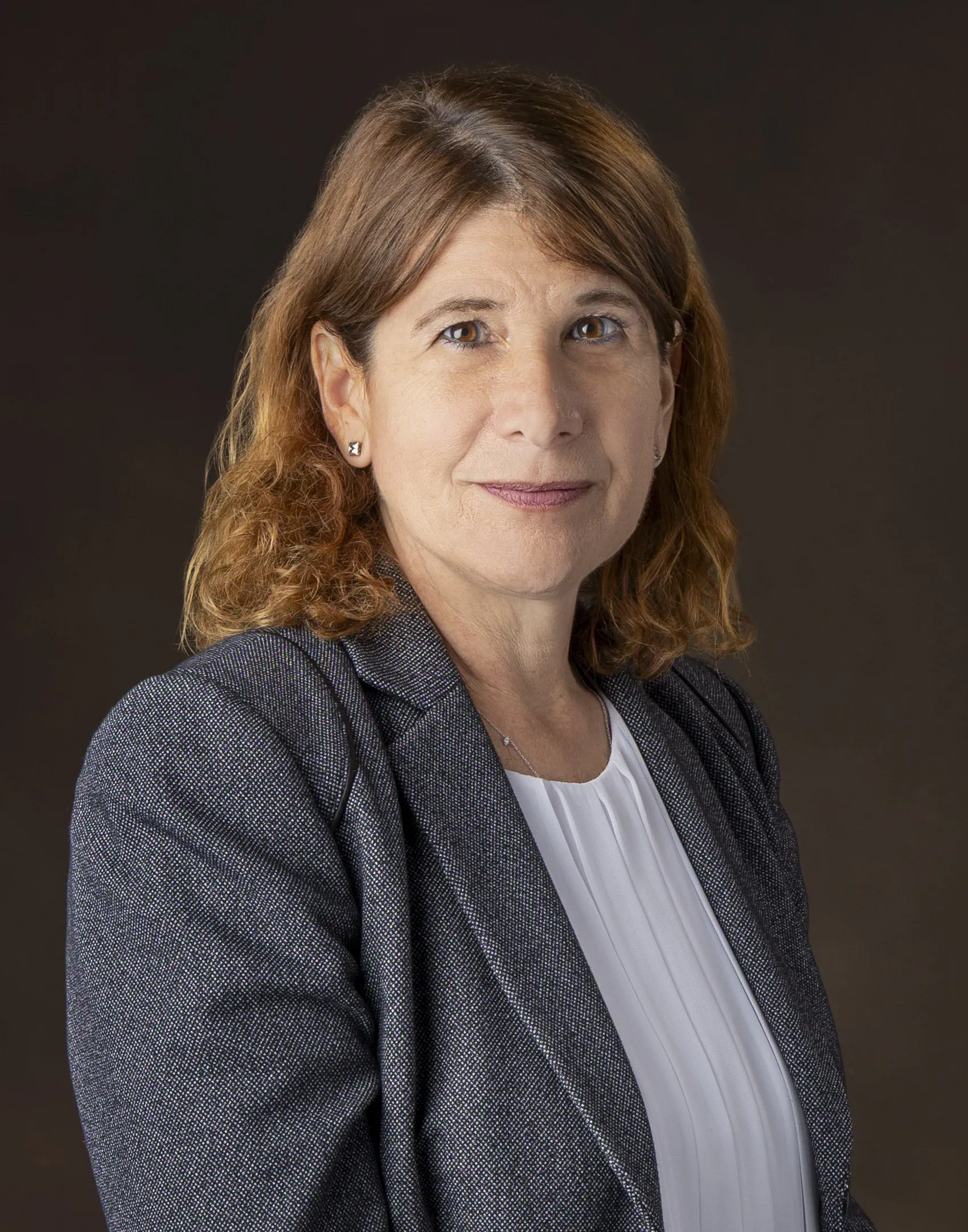 Dr. Jennifer Berne, Madison College president, in a grey blazer with a slight smile, dark background.