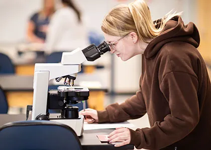 madison college student looking through microscope