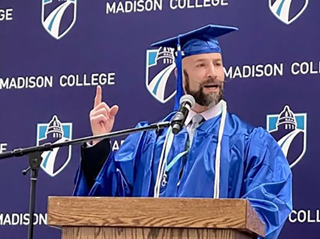 ReEntry Program graduate in cap and gown speaking at a podium