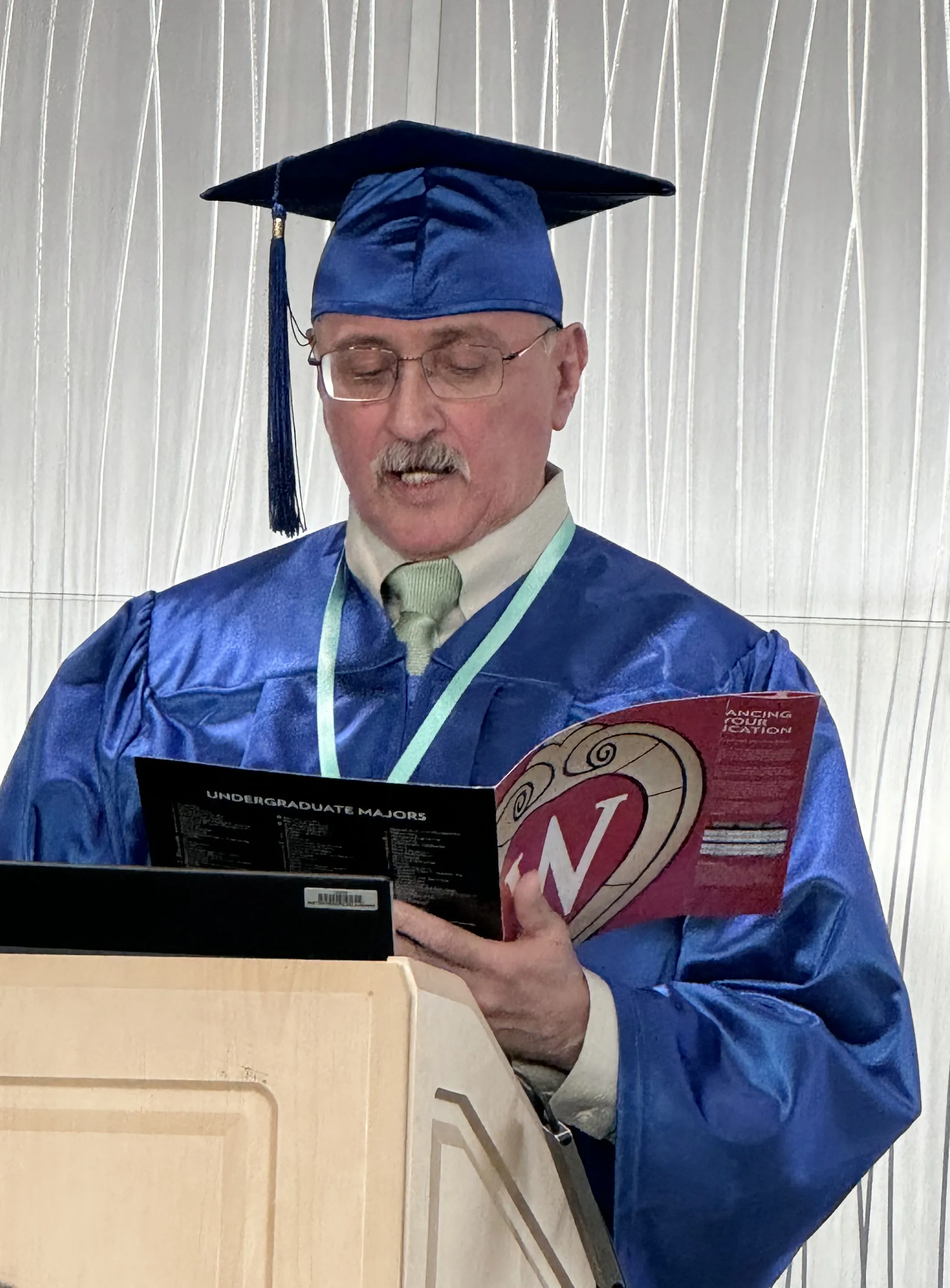 Madison College student Robert Zapata during graduation ceremony wearing a blue cap and gown.
