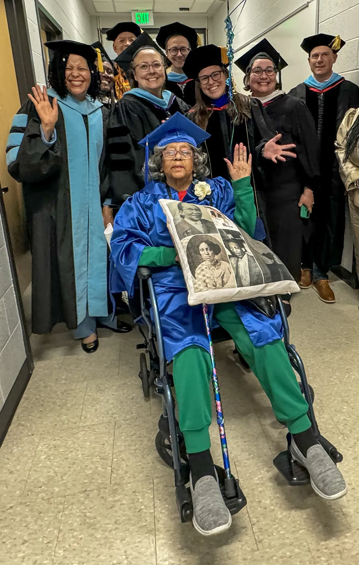 graduate sitting in wheelchair surrounded by school staff
