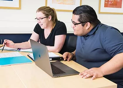Two students seated at a table looking at a business plan.