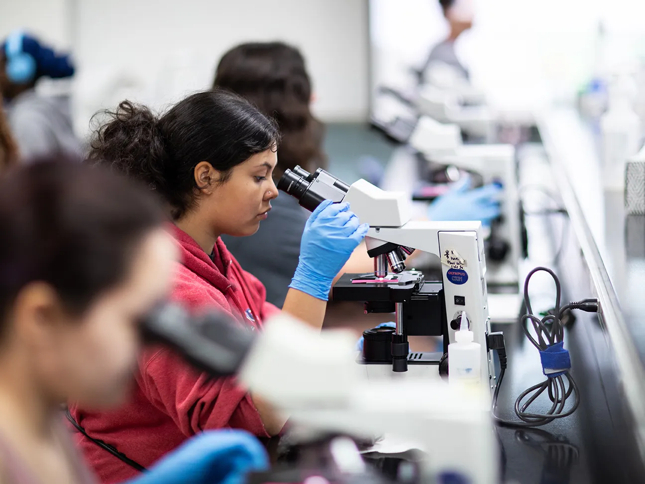 three students looking into a microscope