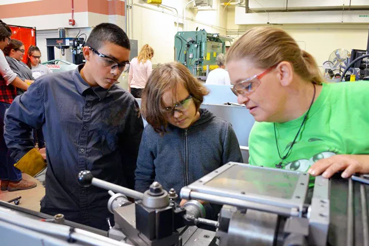 instructor showing students how to use a lathe