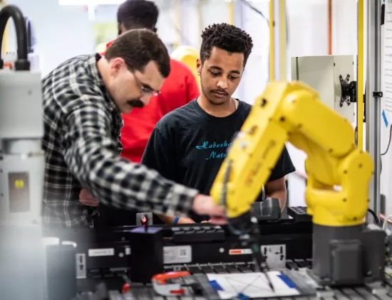 Student watching a person using a machine during the early college stem academy career exploration sessions. 